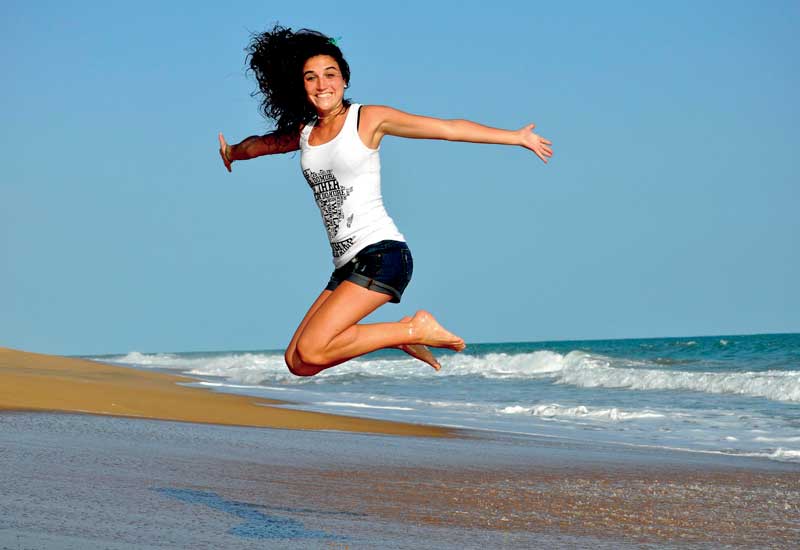 Frau springt am Strand in die Luft