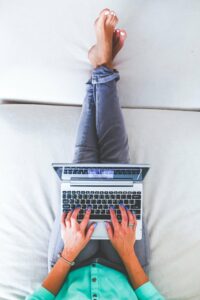 mit Laptop auf dem Sofa sitzen